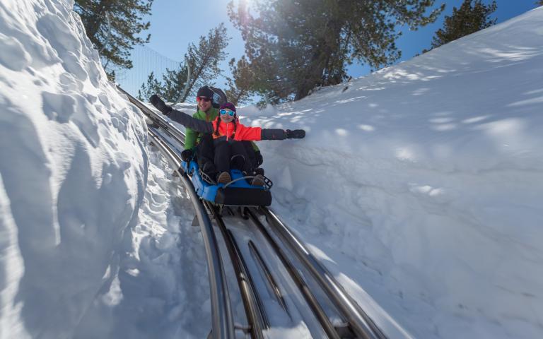 Abfahrt mit dem Nocky Flitzer im Schnee. An den Seiten ist der Schnee über einen Meter hoch. 